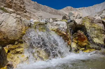 Вода стекает по камням в горном ручье.